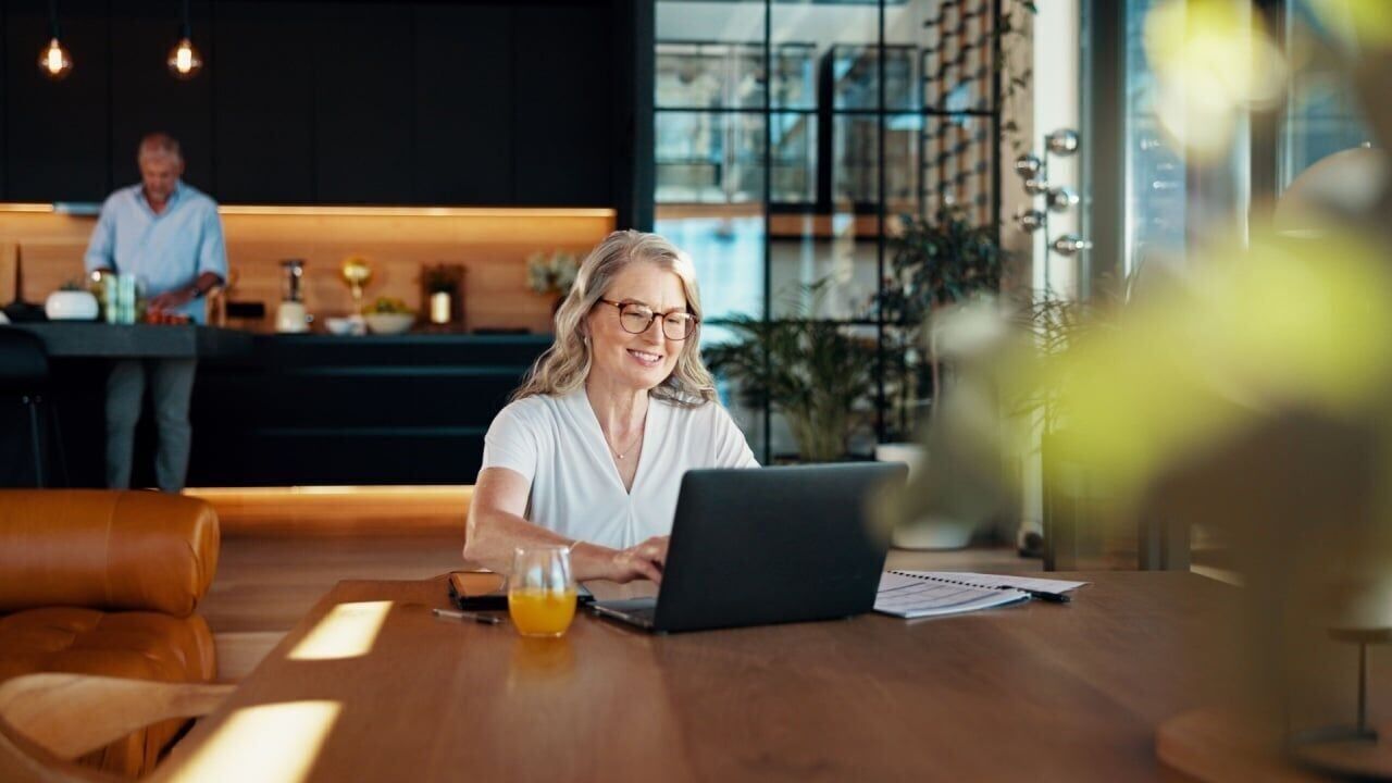 Reading, smile and laptop with old woman at home for social security benefits, annuity growth and retirement fund. Account balance, online banking and 401k withdrawal with person and savings notice