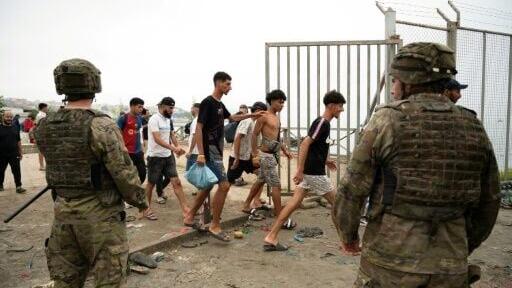 Soldiers watching as migrants cross back into Morocco