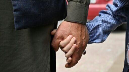 An Afghan father holds his daughter's hand