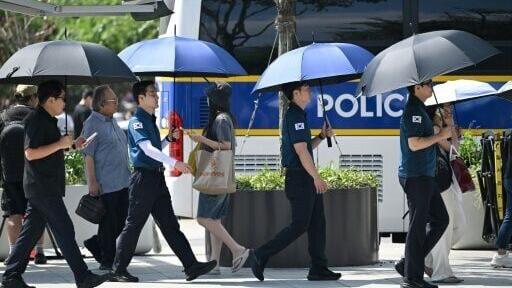 Police officers use umbrellas to shield from the sun on a street in Seoul as a scorching heat wave continues to grip South Korea