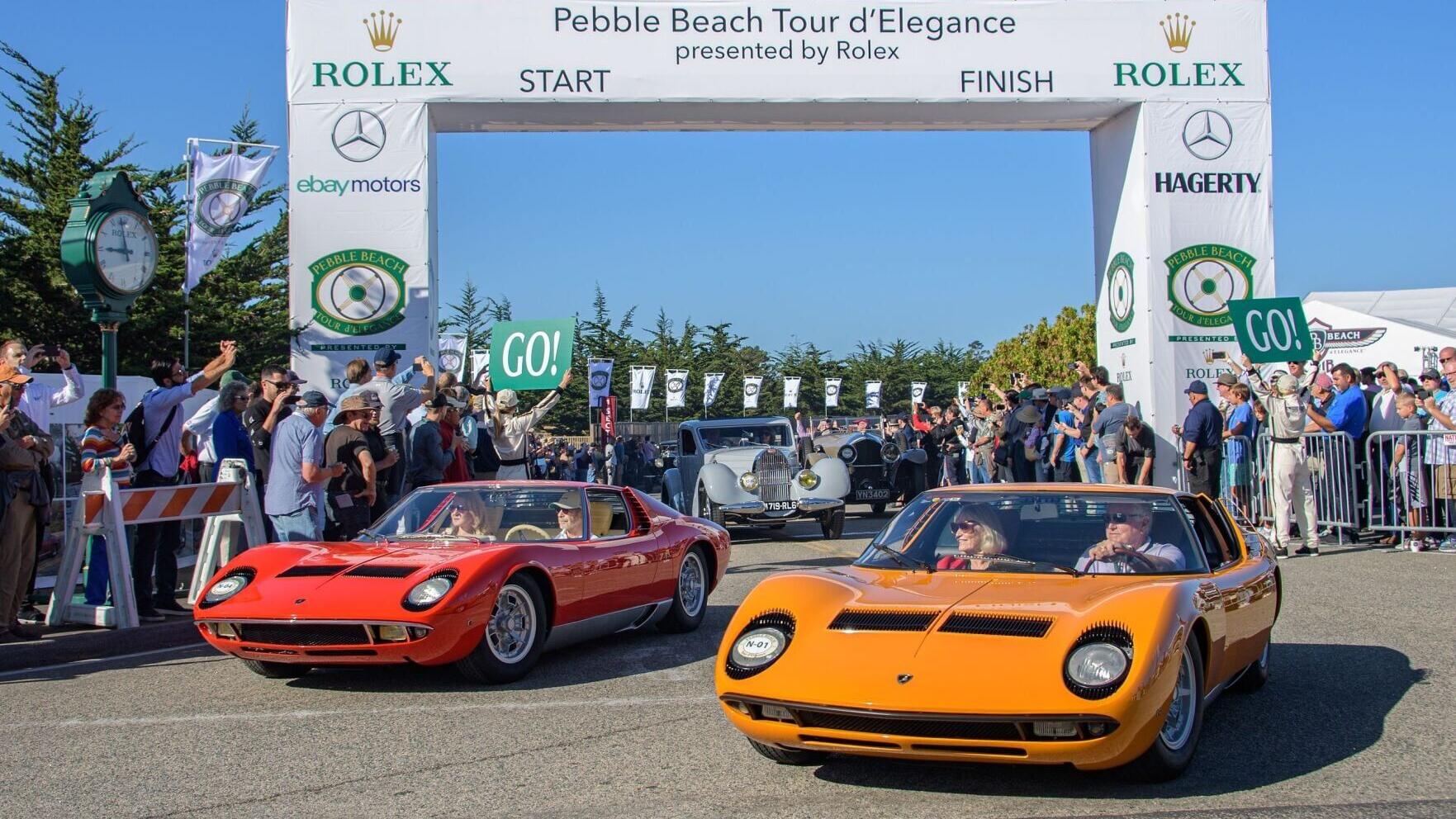 A 1968 Lamborghini Miura Bertone Coupé and a 1967 Lamborghini Miura P400 Bertone Coupé round the turn at the 2019 Pebble Beach Tour d'Elegance. Photo Credit: Kimball Studios / Pebble Beach Concours d'Elegance