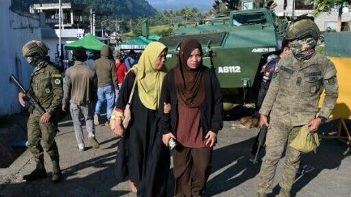 Long lines of voters peacefully queued outside polling stations with armoured vehicles and security personnel standing watch