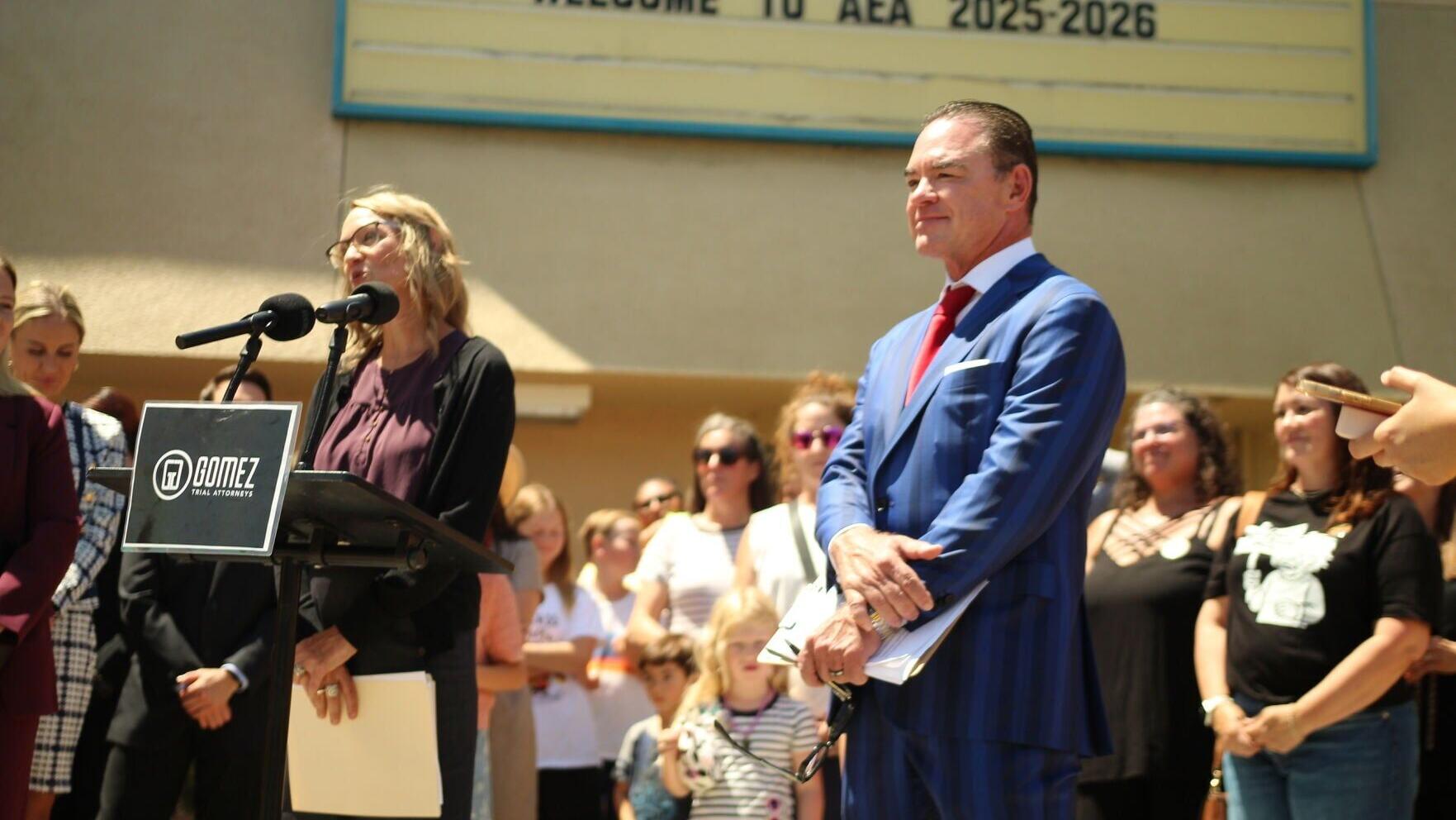 Attorney John Gomez stands alongside client Margaretta Boutserse during a press conference outside Albert Einstein Academies in San Diego on June 12, 2026. Boutserse, a former principal at the school, spoke publicly about her whistleblower retaliation a...