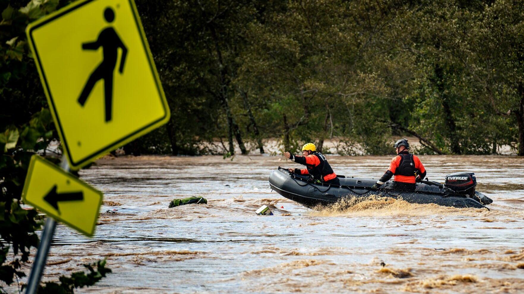 Two members of the Asheville Fire Department's Swiftwater rescue team skill- fully navigate the turbulent waters of the French Broad River as debris from Second Gear clogs their path.
