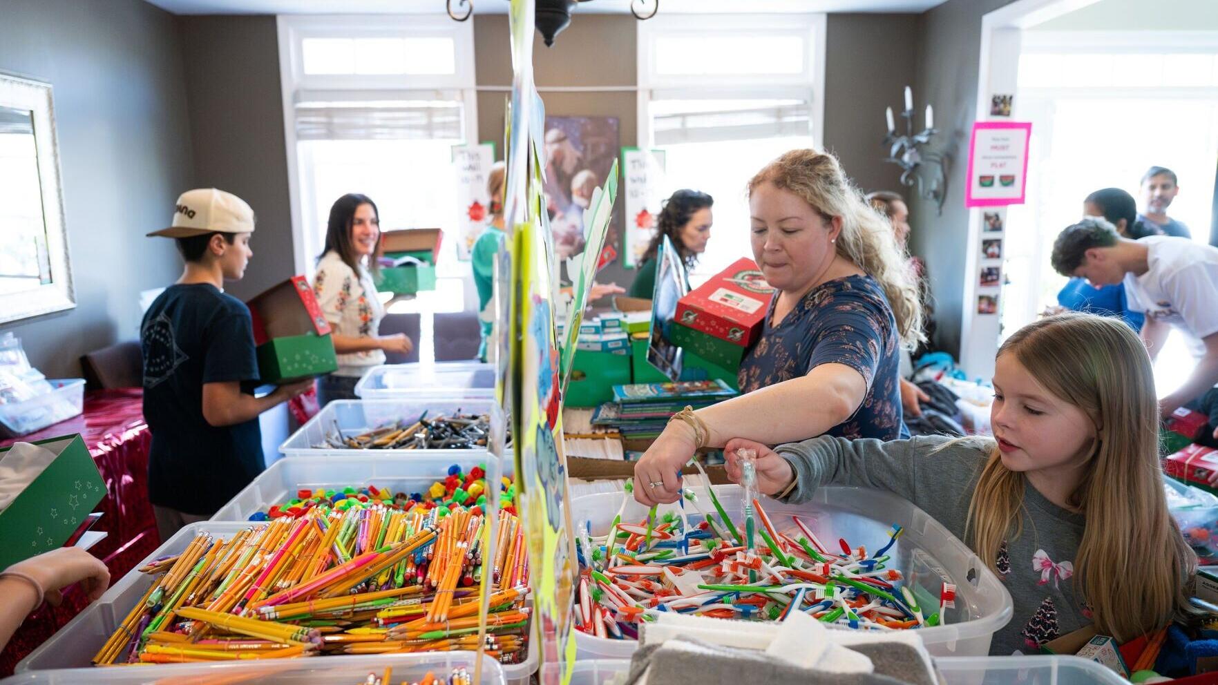 Families pack shoeboxes full of school supplies, fun toys, and personal care items for boys and girls in need.