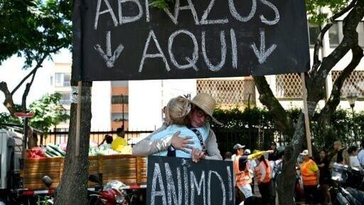 People in Cali, Colombia embrace under a sign reading 'Hugs here,' days after a 7.4-magnitude earthquake devastated parts of the city