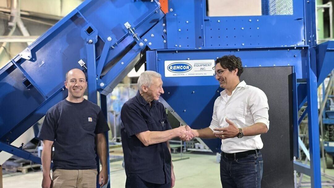 Dan, Dennis, and Sean shake hands in front of the Remcon Material Separation Unit that includes an eddy current and an air knife
