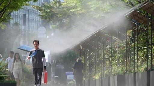 Pedestrians walk along a mist spraying zone to cool off on a street in Seoul as a scorching heat wave continues to grip South Korea