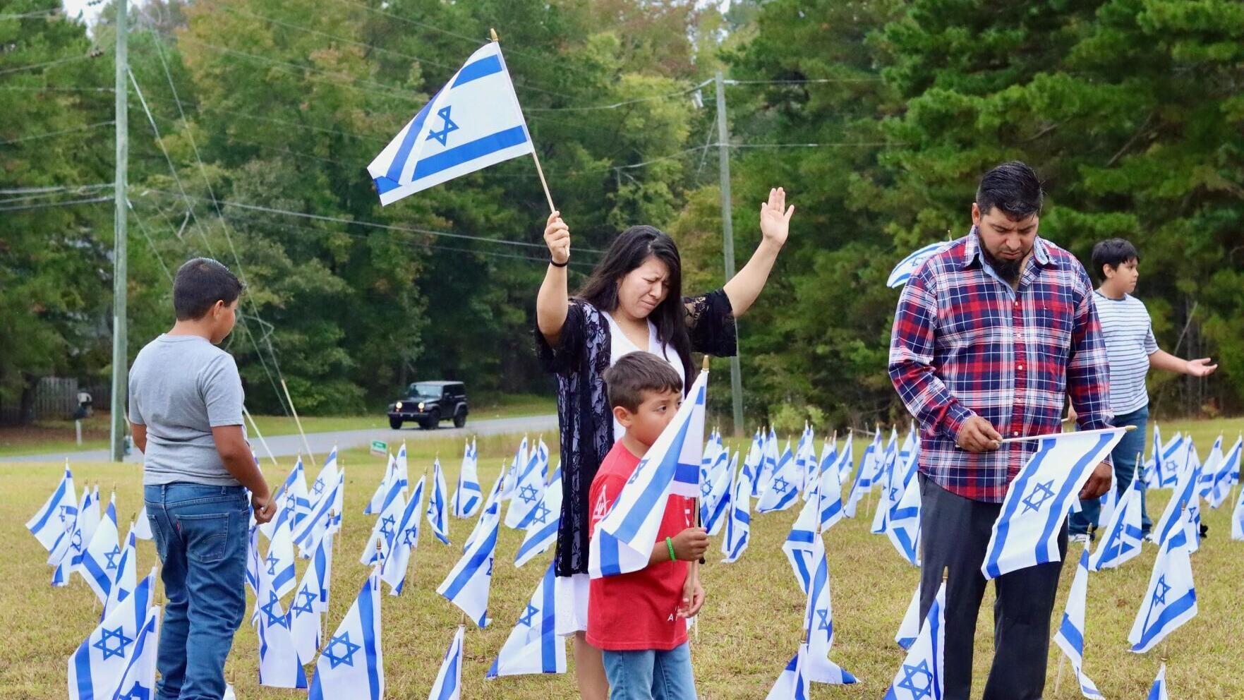 Una familia reza mientras plantando banderas israelíes en la Iglesia Misionera Betel en Commerce, Georgia, como parte del evento Banderas de la Fraternidad en octubre de 2025. Más de 1.350 iglesias, sinagogas y organizaciones participaron en la campaña ...