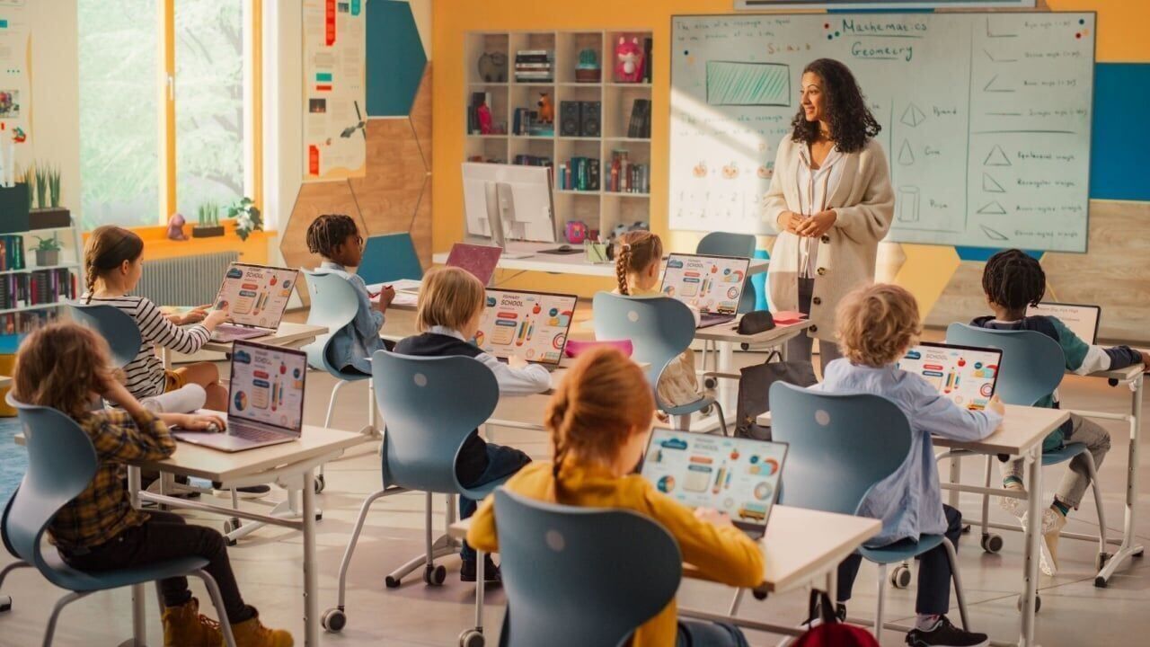 Elementary School Children Learning Basic Computer Knowledge: Teacher Educating Smart Diverse Kids in a Modern Colorful Classroom. Schoolchildren Getting Experience with Technology