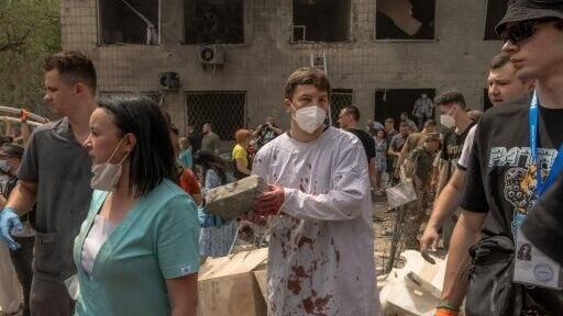 Volunteers, including medical staff, help emergency personnel to clear the rubble of a destroyed building at Ohmatdyt Children's Hospital in Kyiv