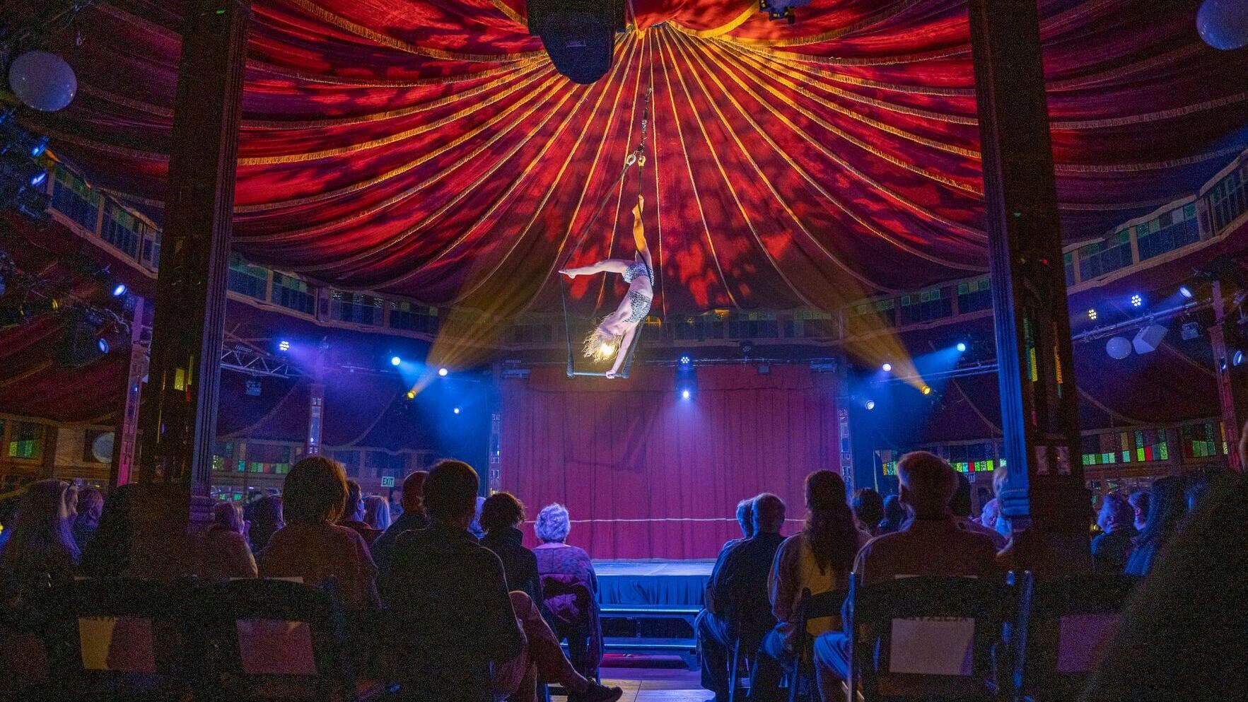 An aerialist soars high above the crowd in the Spiegeltent at the ESL Rochester Fringe Festival. Photo Credit: Keith Bullis.