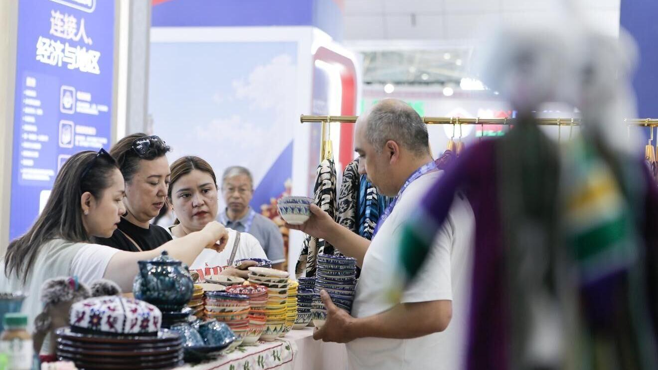 Visitors inspect products at the Uzbekistan booth on June 26. SHI FENG / XINHUA