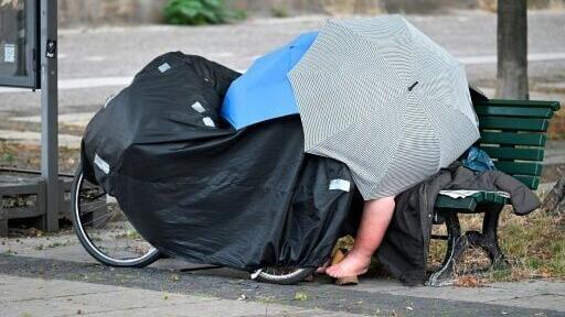 A homeless person sleeps on a Berlin park bench