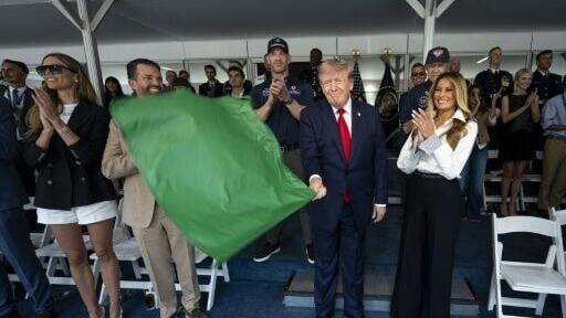 US President Donald Trump waves the green flag to start the Freedom 250 Grand Prix with First Lady Melania Trump at his side for the IndyCar race over the streets of Washington