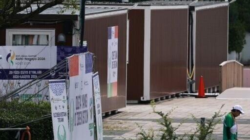 A man walks past temporary container huts being used to house athletes for the 2026 Asian Games at the Garden Pier in Nagoya