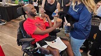 Army Veterans Lyndsey Hawk-Nelson and Dustin Hawk greet a puppy during an open-house at Wounded Warrior Project's San Antonio office. Lyndsey serves as her husband's caregiver after he survived a stroke.