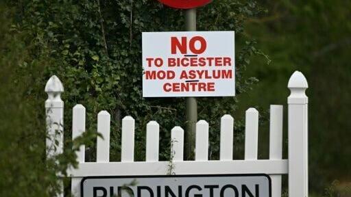A sign for the village of Piddington is pictured next to another saying 'No to Bicester MOD asylum centre'