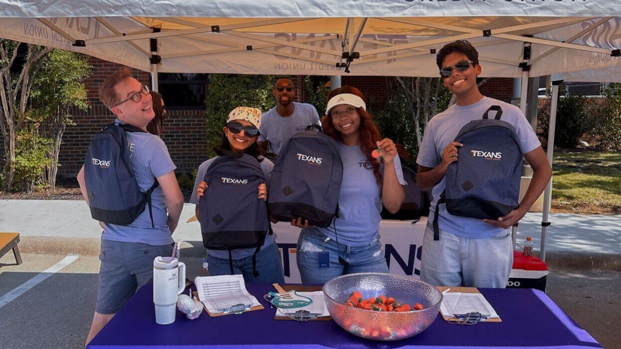 Texans Credit Union employees pose with backpacks stuffed with school supplies that were distributed to families.