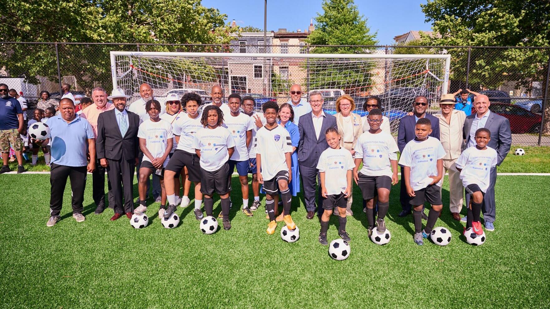 Representatives from Children's Hospital of Philadelphia, Embassy of the United Arab Emirates, Philadelphia Parks and Recreation, gather with community members to celebrate the opening of Conestoga Park soccer field in West Philadelphia.