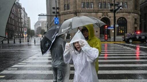 People visit the Bund in Shanghai in heavy rain, a day after Typhoon Dolphin made landfall in Shanghai, on August 10, 2026.