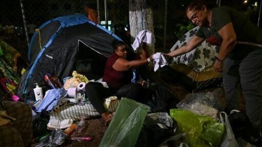 A woman receives clothes in a makeshift camp in Cali, Colombia, which suffered major damage from the Aug. 10 earthquake