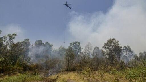 A helicopter drops water on burning forests and land in the Tegal Arum and Guntung Damar areas, Banjarbaru, in Indonesia’s South Kalimantan province on September 19, 2026.