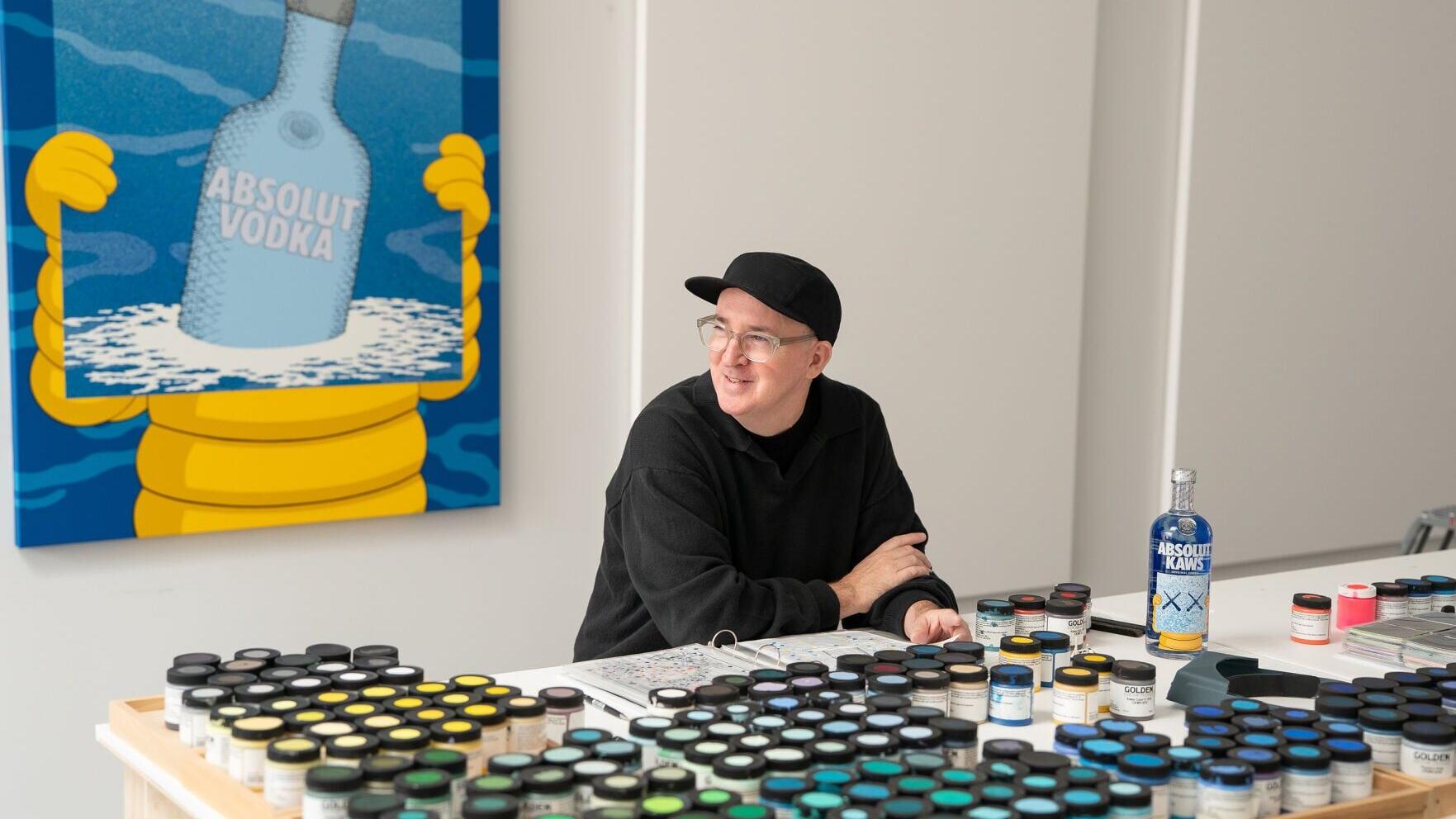 KAWS in his Brooklyn studio with the specially commissioned painting that inspired the ABSOLUT KAWS Artist Edition Bottle.