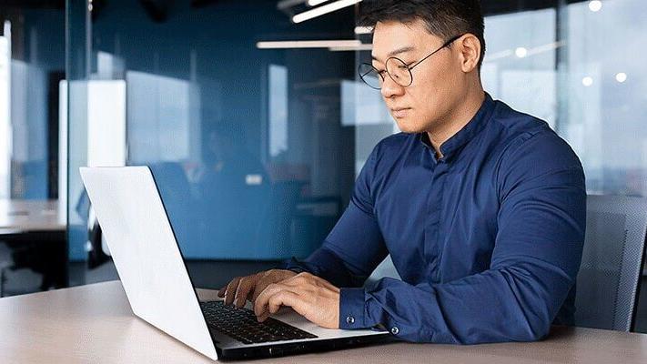 A man who is looking at a white laptop