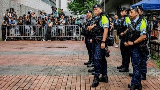 Police officers stand near the media area outside the West Kowloon Magistrates' Courts ahead of the verdict in the national security trial of two pro-democracy Tiananmen activists in Hong Kong