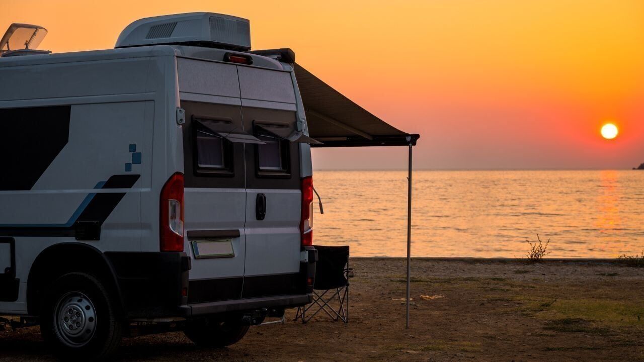 Campervan is parked on the beach at sunset. Campervan is parked on the beach next to the sea – wild camping in Croatia, Montenegro, Albania or Greece. Summer road trip