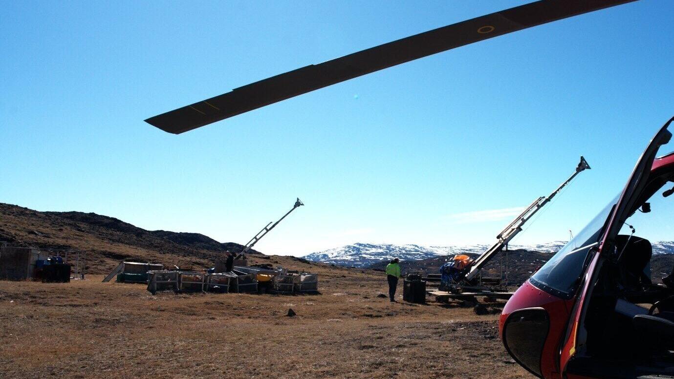 Drill rigs and logistics at Sarfartoq: View across the ST1 plateau showing the  two stored diamond drill rigs, field equipment and the Air Greenland helicopter used during the May 28, 2026 site visit, illustrating the quality of existing drilling and lo...