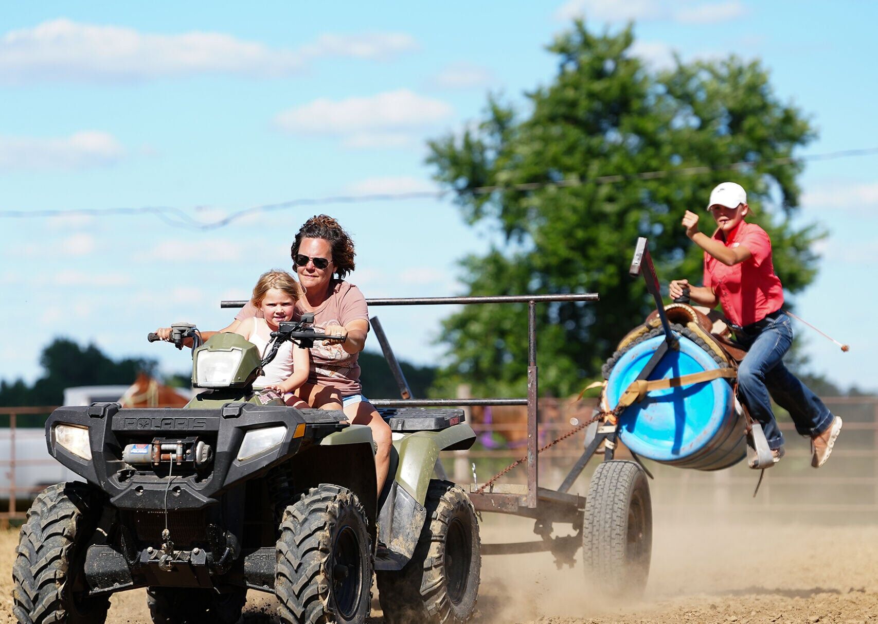 Libby Wood, center, drives an ATV with Treylea Couch, 4,