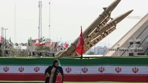 A woman stands next to Iranian-made Zolfaghar missiles displayed at Azadi Square in Tehran on July 24, 2026