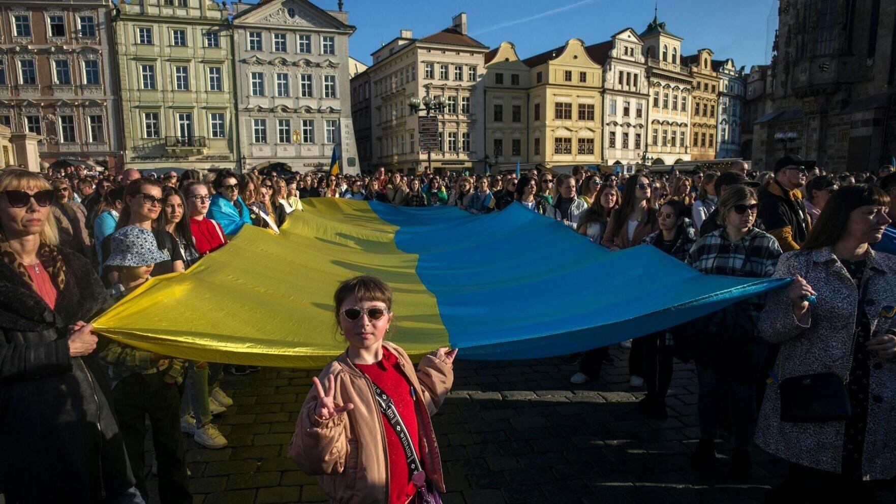 A crowd of people in Prague display a Ukrainian flag as they watch the 'Save Ukraine – Stop War' concert  in 2022.