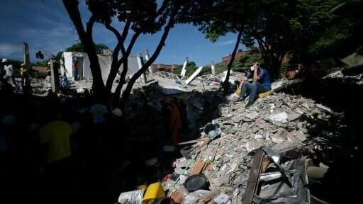 A rescuer sits on the rubble of a collapsed building in Cali, Colombia, which was hit by the strongest quake this century