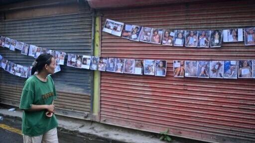 A woman looks at photographs of the missing and dead following flash floods in Nepal, outside a hospital in Kathmandu