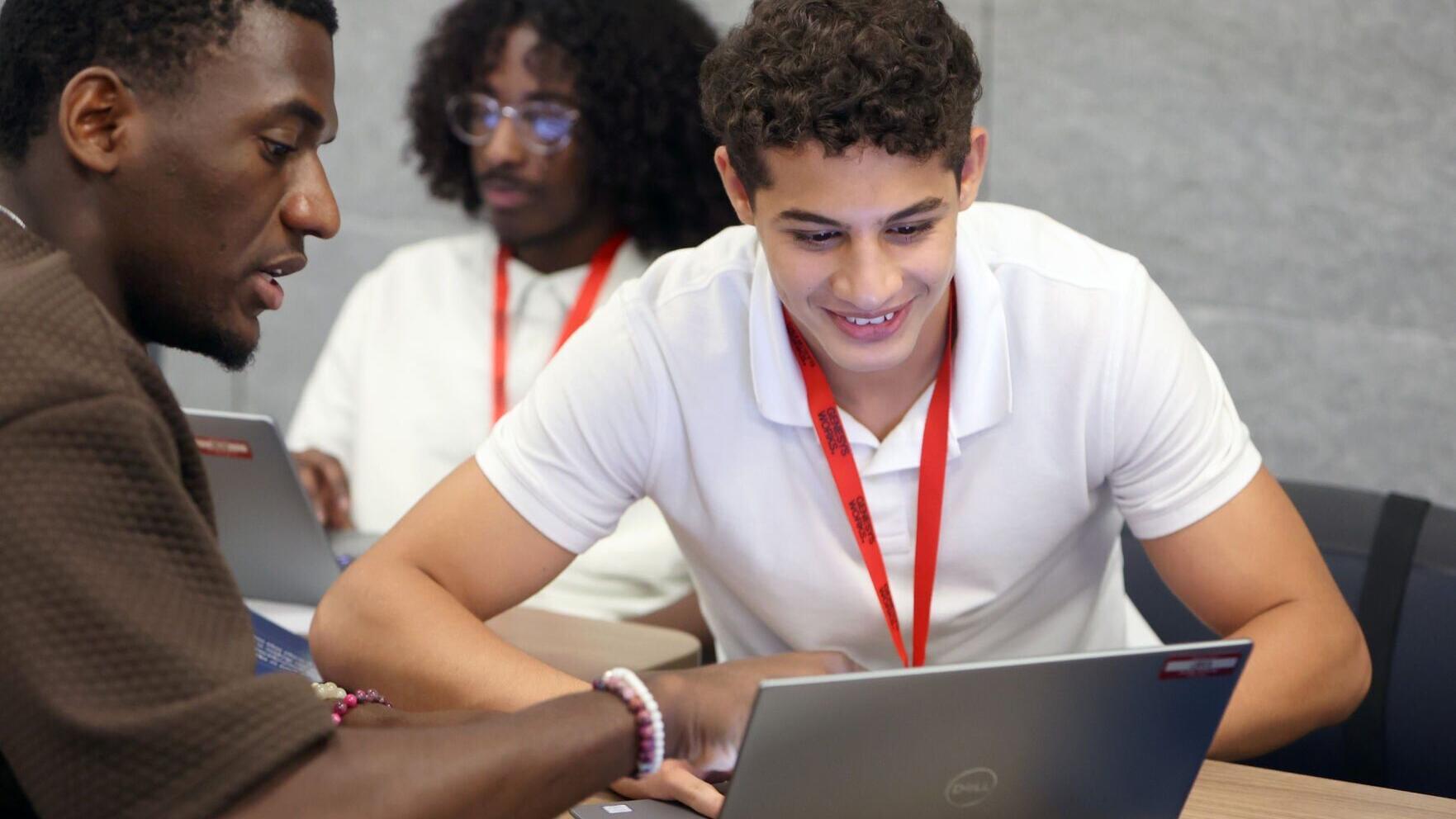 A Genesys Works trainer guides a student through technical training, building the skills and workplace readiness needed to succeed in a year-long paid corporate internship.