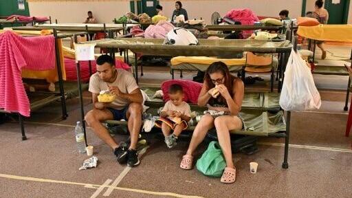 Evacuees eat ata sports centre where they are sheltering from wildfires