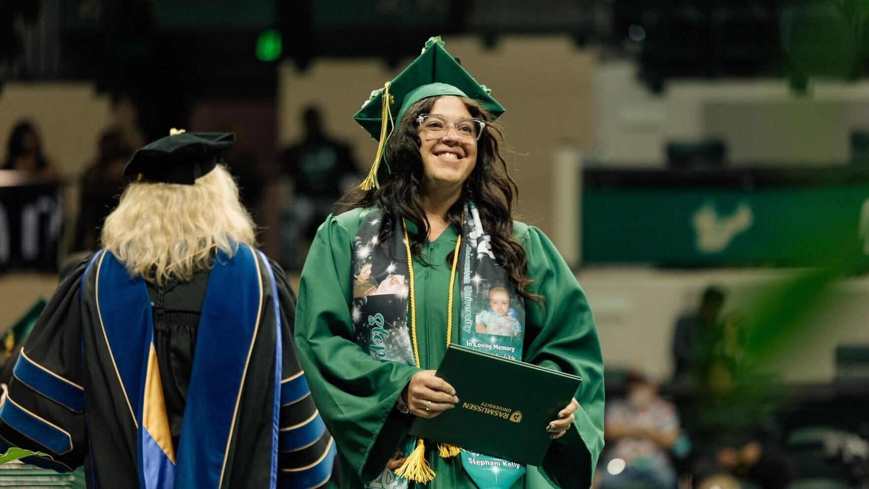 A Rasmussen University graduate crosses the stage during the 2025 Florida Commencement Ceremony at the Yuengling Center in Tampa, Florida, celebrating the culmination of their hard work and academic achievement.