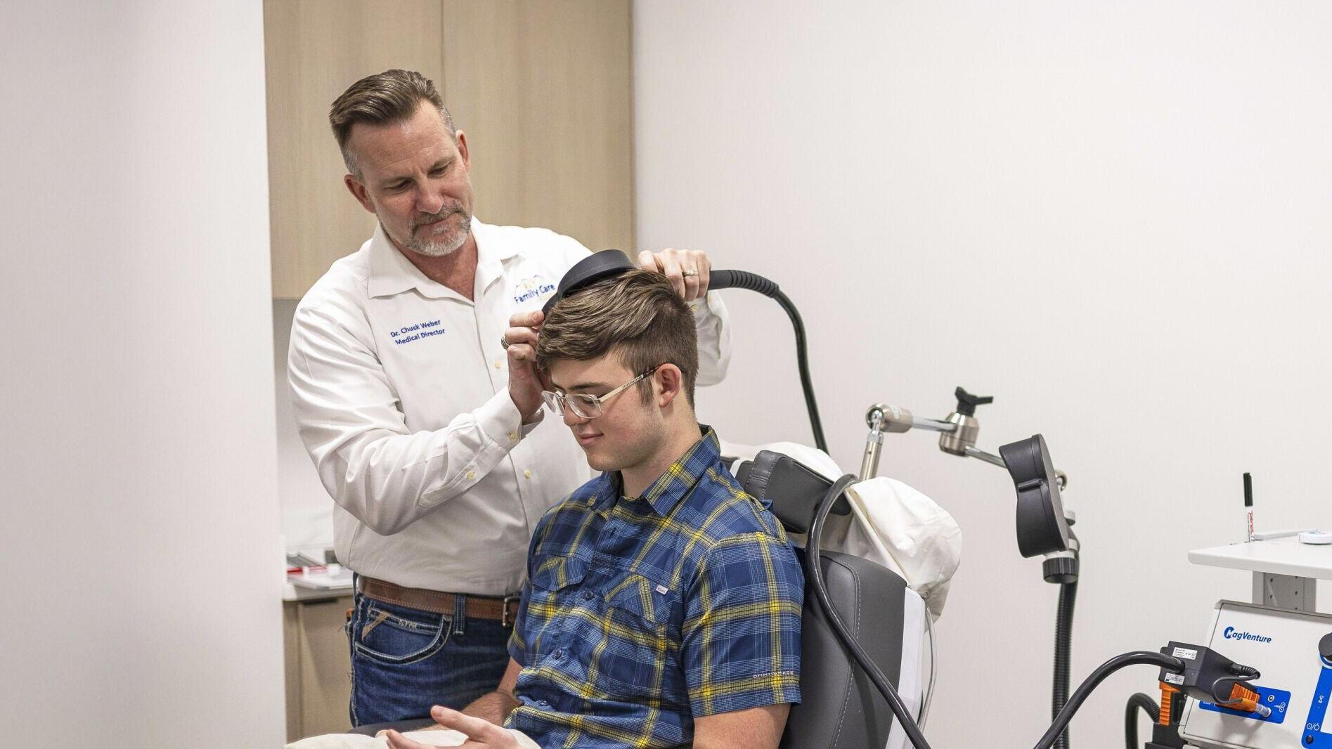 Dr. Chuck Weber performs TMS on a male teen patient.