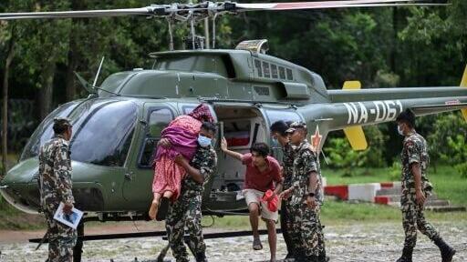 An Army personnel carries out an elderly woman from a helicopter during a rescue operation in the aftermath of Nepal-Tibet flash floods