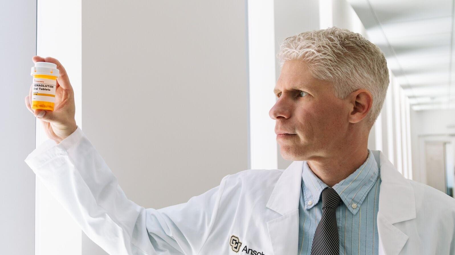 Photo of Joseph Schacht, PhD, at CU Anschutz holding up bottle of semaglutide
