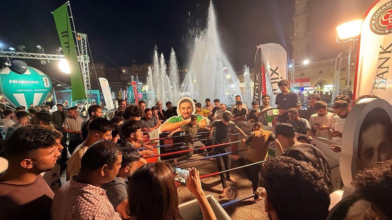 Football fans gather around football challenges at an Infinix World Cup community event in Iraq.