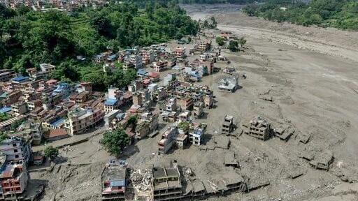 Buildings near Nepal's border with Tibet were buried in a deadly flood that left hundreds missing
